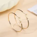 Gedetailleerd overzicht van stijlvolle gouden creolen met zwart emaille, minimalistisch. - Goud + Zwart