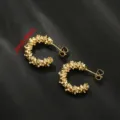 Gedetailleerde close-up van onregelmatige gestructureerde gouden oorbellen met uniek design. - Stijl 2 / Goud