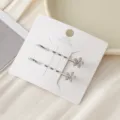 Gros plan détaillé de pinces à cheveux argentées avec fleurs en zircon sur carte blanche. - Blanc Fleur