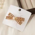 Primer plano de una elegante pinza para el pelo con lazo de diamantes y perla. - Lazo Dorado con Perla