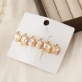 Close-up detail of luxury crystal apple hair clip with gold metal finish on white card. - Gold Apple Heart Style