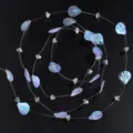 Vue détaillée de perles de coquillage irisées sur fil de pêche, idéal pour loisirs créatifs. - 1 Mètre / Morceau de coquillage + cristal triangulaire 6 mm