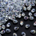 Primer plano de cuentas de cristal transparentes en forma de lágrima con brillo iridiscente. - Blanco AB