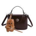 Dark brown leather top-handle crossbody bag with cute plush dog charm and chic metal lock clasp. - Single Bag / Coffee