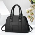 Vue détaillée du sac à main en cuir noir texturé avec anneaux et design central. - Noir