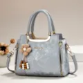 Graue elegante Handtasche Detailansicht mit Holzperlen Blumenanhänger und goldener Hardware. - Länge 24 Breite 12 Höhe 19 Griff 12cm / Grau
