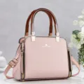 Detailaufnahme der rosa gewebten Handtasche mit braunen Griffen und goldenen Beschlägen. - Rosa