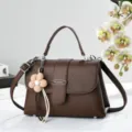 Vue détaillée du sac à bandoulière marron pour femme avec grain litchi et charmant pendentif. - Café