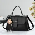 Gros plan détail du petit sac carré noir effet litchi rétro avec pendentif fleur charmant. - Noir