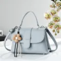 Hellblaue Damen Umhängetasche aus Leder mit Litschi-Muster und Blumen-Anhänger. - Blau