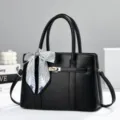 Elegante schwarze Damenhandtasche mit schickem gestreiften Schal und goldener Hardware. - Schwarz