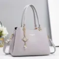 Detailed close-up of a stylish grey leather women's handbag with metal chain charm and handles. - 28x13x20cm / Gray
