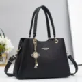 Close-up of black leather handbag detail, featuring gold hardware and elegant pearl charm. - 28x13x20cm / Black
