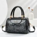 Close-up detail of black patent leather handbag with embossed flowers and gold clasp. - L24 W13 H16 Handle 13cm / Black