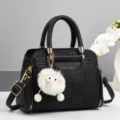Schwarze Schultertasche aus Leder mit geometrischem Muster und niedlichem Plüsch-Anhänger. - Schwarz