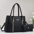 Black synthetic leather handbag detail showing metal logo and matching small purse. - Black