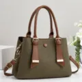 Dettaglio borsa in tela verde con manici in pelle marrone e finiture metalliche dorate. - 28x12x20cm (Manico 15cm) / Verde