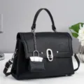 Detailansicht der schwarzen Lederhandtasche mit silbernem Metall und schickem Mini-Anhänger. - Schwarz