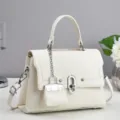 Detailed view of white leather shoulder bag, elegant silver hardware and mini charm. - Off White
