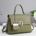 Olive green leather handbag detail, metal clasp and mini bag charm, textured surface. - Green