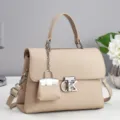 Beige leather top handle handbag with stylish metal clasp and miniature bag charm accessory. - 25x10x18cm / Apricot