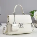 Close-up detail of white leather handbag with metal lock and mini charm pendant. - 25x10x18cm / Off White