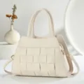 Vue détaillée de l'élégant sac à main en cuir tressé beige avec poignées et bandoulière. - Blanc