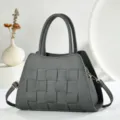 Vue rapprochée du sac à main en cuir tissé gris foncé, mettant en valeur sa texture et détails. - Gris