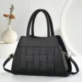 Vue détaillée du sac à main en cuir tissé noir, design classique à poignée et bandoulière. - Noir