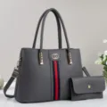 Graue Handtasche Detail aus Narbenleder mit rot-blauem Streifen, Henkeln und passender Tasche - Grau