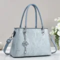 Elegant light blue women's crossbody handbag with top handles and stylish quatrefoil charm. - Light Blue