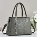 Grüne Damen Handtasche Detailansicht mit Vintage Streifen Textur, Metallgriffen und Anhänger. - Grün