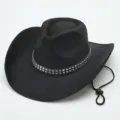 Detail van vintage zwart suède cowboyhoed met metalen klinknagelband en verstelbaar koord. - M (56-58cm) / Zwart