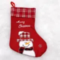 Close-up of red Christmas stocking featuring plaid cuff, snowman embroidery and festive text. - Snowman