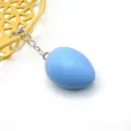 Primo piano portachiavi uovo di Pasqua in legno blu pastello con anello metallico argentato. - Blu