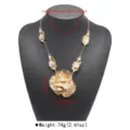 Detailed view of the gold statement necklace with irregular leaf and flower pendants. - 3D Floral Necklace (N14105) / Gold