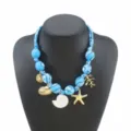 Blue fabric wrapped beaded necklace detail with ocean charms like shell and starfish. - Blue