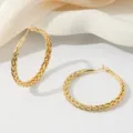 Detailopname van vergulde gevlochten grote creolen, elegante minimalistische sieradenstijl voor dames. - 50mm Stijl / 18K Verguld