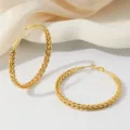 Detailopname van de elegante vergulde grote gevlochten creolen oorbellen met een fijne textuur. - 60mm Stijl / 18K Verguld