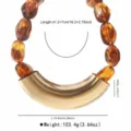 Detailed view of handmade resin beaded necklace with large gold curved metal pendant and specs. - Amber