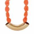 Close-up of chunky orange resin beaded necklace with gold curved pendant detail shot. - Orange