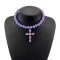 Primo piano della collana girocollo con perline viola e ciondolo a croce di cristallo. - Viola