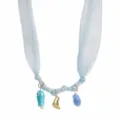 Vue détaillée du collier en ruban de tissu bleu clair avec de charmants pendentifs dorés. - Bleu ciel