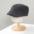 Detailed closeup of dark grey herringbone wool ivy flat cap displayed on wooden stand. - M (56-58cm) / Beret (CK-45) / Black