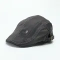 Nahaufnahme der dunkelgrauen Schiebermütze mit Stickerei und Metall-Totenkopf-Verzierung. - M (56-58cm) / Grau