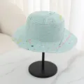 Close-up view of a light blue straw hat featuring colorful paint splatter details and flat top. - M (56-58cm) / Cyan