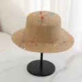 Detail view of the summer flat top straw hat featuring creative colorful paint splash design. - M (56-58cm) / Khaki