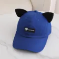 Primer plano detallado de la elegante gorra de béisbol azul con orejas de gato negras y etiqueta. - Talla Única para Adultos / Azul zafiro