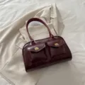 Sac à main bordeaux en similicuir avec deux poches avant et fermoirs dorés élégants. - Rouge