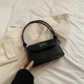 Chique zwarte leren okseltas voor dames met elegante strik metalen detail modieuze tas. - Zwart